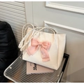 Bolso tote crema con lazo rosa y asa de cuerda trenzada en silla moderna - Blanco