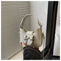 Detail of a creamy white mini handbag featuring a silver metallic bow and chain strap - White