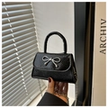 Dettaglio micro borsa nera con goffratura coccodrillo, fiocco argento e catenina - Nero