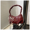 Close-up of burgundy handbag featuring pleated handle and pearl bow detail - Red
