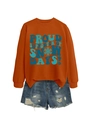 Détail du sweat-shirt orange avec texte bleu Proud Supporter of Snow Days et short en jean - Orange Brûlé
