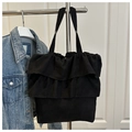 Detalle del bolso tote de lona negra con volantes plisados dobles y diseño minimalista - Negro