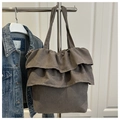 Detalle de bolso tote gris con volantes en gamuza sintética colgado en percha metálica - gris oscuro