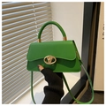 Detalle de bolso trapezoidal verde brillante con cierre giratorio dorado y textura de cuero liso - Verde