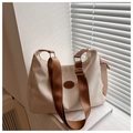Close-up of beige crossbody bag with fashion leather patch and brown woven strap details - White