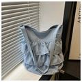 Detalle del bolso tote azul claro con volantes escalonados de tela en un alféizar minimalista - Azul