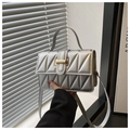 Détail d'un sac bandoulière argenté matelassé avec surpiqûres et boucle dorée - Argent