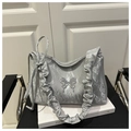 Gros plan d'un sac argenté avec bandoulière à volants et pendentif papillon chic - Argent