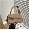 Primer plano de un bolso cuadrado beige minimalista con detalle de lazo y correa - Caqui