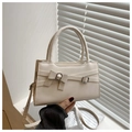 Detalle de bolso color crema con lazo decorativo y hebillas metálicas plateadas - Blanco