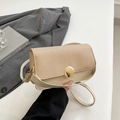 Chic beige leather and straw crossbody bag with gold round buckle shown in hand - Khaki