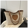 Detailansicht der Stroh-Tasche mit Herz-Lederpatch auf weißem Stoffhintergrund - Braun