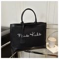 Détail du sac cabas en toile noire avec signature Frida Kahlo sur un chariot moderne - Noir