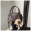 Detailed shot of dark brown Boston bag with lucky embossed texture and plush lamb pendant - Coffee With Charms