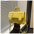 Detail van een felgele crossbodytas met scrunchie handvat en rechthoekige gespsluiting - Geel