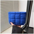 Primer plano de un bolso acolchado azul brillante sostenido a mano con textura de nailon - Azul