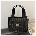 Primer plano de bolsa de almuerzo de tweed grueso con textura negra y dorada y etiqueta - Negro