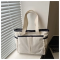 Detailed close-up of a beige corduroy tote bag with side pockets on a window sill - White