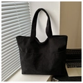 Detail of black corduroy tote bag showing front pocket and ribbed texture in study setting - Black