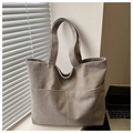 Close-up of light grey corduroy tote bag texture and front pocket detail - Gray