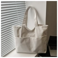 Close-up of beige corduroy tote bag showing soft ribbed texture and front pockets - White