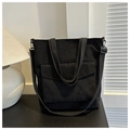 Primer plano detallado de un bolso tote de pana negra con bolsillo y correa ajustable - Negro