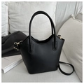 Detalle del bolso tipo cubo minimalista en cuero negro mate con herrajes dorados - Negro