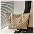 Detailopname van de tote bag met M-monogram en gouden logo-hanger op een vensterbank - Wit