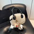 Cream square crossbody bag with black handles and cute bear charm in stylish lifestyle setting - With Pendant / White