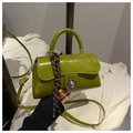 Detail of bright green glossy handbag with gold twist lock and woven charm accessory - Green With Pendant