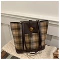 Gros plan d'un sac cabas à carreaux avec boucle dorée N sur un tissu en tweed - Plaid Jaune