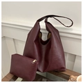 Detalle del juego de bolsos tote granate con estuche a juego sobre escritorio de madera - Rojo