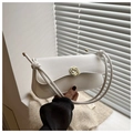 Close-up of white shoulder bag featuring a golden spiral lock and knotted handle detail - White