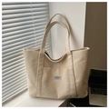 Close-up of beige corduroy tote bag featuring vertical texture and logo patch detail - Khaki