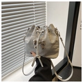 Détail du sac seau gris clair avec breloque papillon argentée et cordon de serrage - Argenté