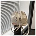 Close-up of a white drawstring bucket bag with a stylish silver metal bow detail - White