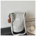 Detail der grauen Bucket-Bag aus Lammwolle mit Plüsch-Pompon und ZYJ-Design-Label - Grau Mit Anhänger