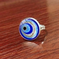 Adjustable silver Turkish Evil Eye talisman ring on a rustic dark wood surface - Deep Blue Concentric Evil Eye Style (JY009127-4)