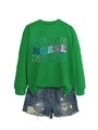 Detail eines grünen Nurse-Sweatshirts mit Kunstdruck und zerrissenen Denim-Shorts - S / Grasgrün