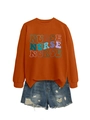 Detail of orange sweatshirt with colorful nurse print paired with distressed denim shorts - S / Burnt Orange
