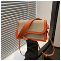 Detailed view of cream fabric bag with orange leather trim and modern wavy flap design - Orange
