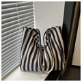 Dettaglio di una borsa tote in tela a righe blu e beige su un davanzale soleggiato - Blu
