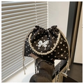 Detailed view of polka dot bucket bag with pearl handle and metal bow decoration - Black