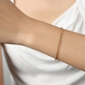Pulsera fina de acero de titanio dorado con cuentas en la muñeca de una mujer - Pulsera de Esmalte Marrón / Dorado