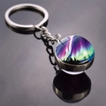 Detail view of aurora borealis glass ball keychain with forest silhouette on black surface - Aurora Forest Silhouette Style (JY009320-4)
