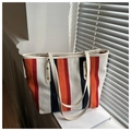 Close-up of striped canvas tote bag with leather handles on a bright sunny windowsill - Orange