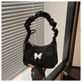 Close-up of black ruched texture handbag featuring a silver butterfly charm and ruched strap - Black
