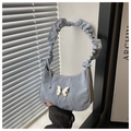 Detail of light blue pleated shoulder bag featuring a silver metal butterfly ornament - Blue