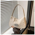 Detalle del bolso de hombro crema con textura arrugada y placa de metal con logotipo - Blanco