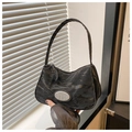 Detalle del bolso de hombro negro con textura arrugada y placa metálica plateada - Negro